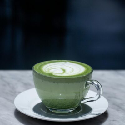 A beautifully crafted matcha latte in a glass cup sits on a marble table, offering a perfect blend of elegance and flavor.