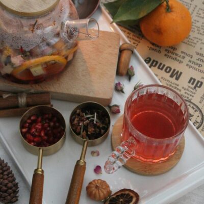 A warm autumn tea setup with citrus fruits and pomegranate seeds.