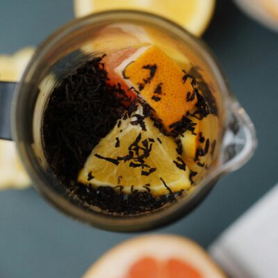 Overhead view of a tea pot with citrus slices and loose leaf tea, perfect for a refreshing homemade brew.